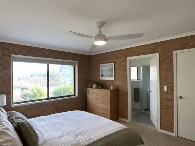 Ceiling fan on a white bedroom ceiling above a brick-walled room in Croudace Bay