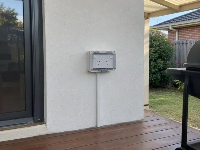 Outdoor double power point in weatherproof box on a white exterior wall beside a sliding door in Belmont